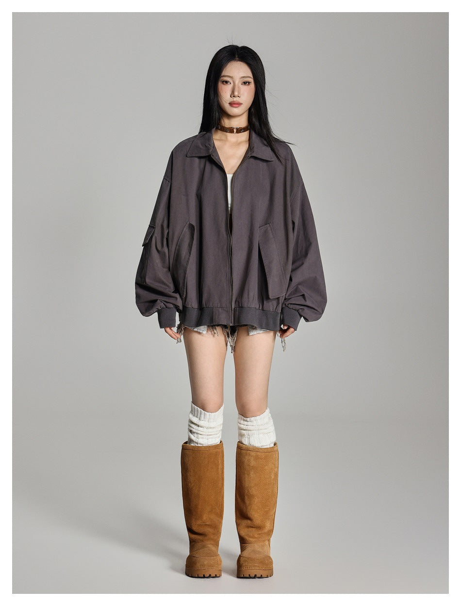 Model wearing an oversized gray zip jacket with ribbed hem and cuffs over a white top, denim shorts and tall boots