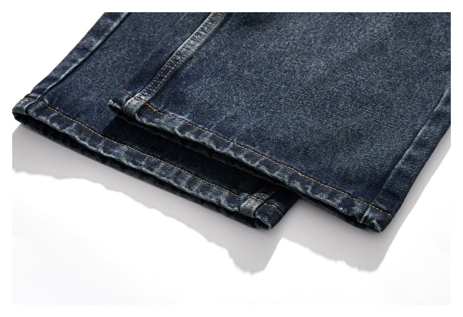 Close-up of dark washed jeans showing double-stitched, folded hems.