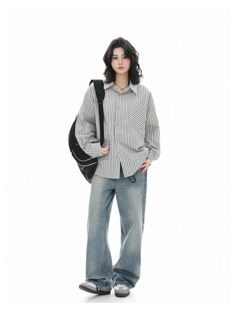 Full-length front view of a model wearing a blue-gray striped button-up shirt and loose light-wash jeans.