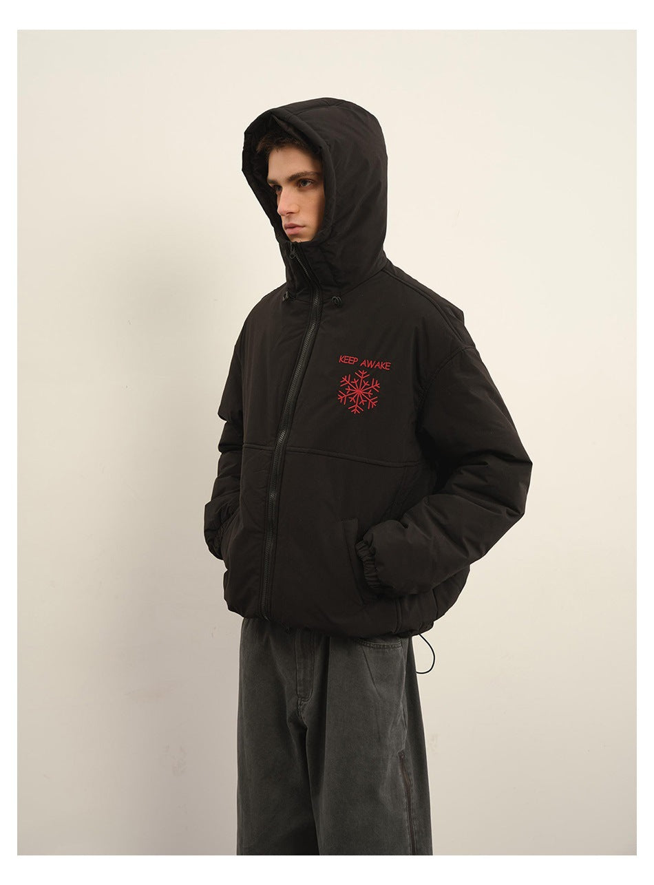 Model wearing a black hooded zip jacket with red “KEEP AWAKE” lettering and snowflake embroidery.