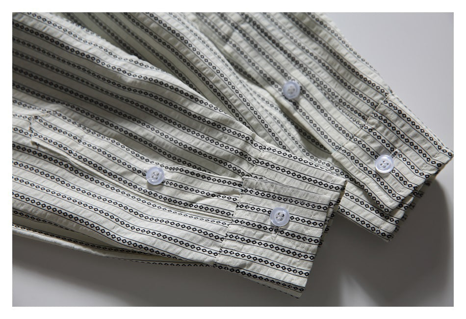 Close-up of the cream shirt's buttoned cuffs and black geometric stripe pattern.