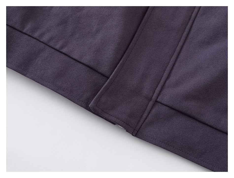 Close-up of a dark plum garment's textured fabric, stitched panels, and folded hem.