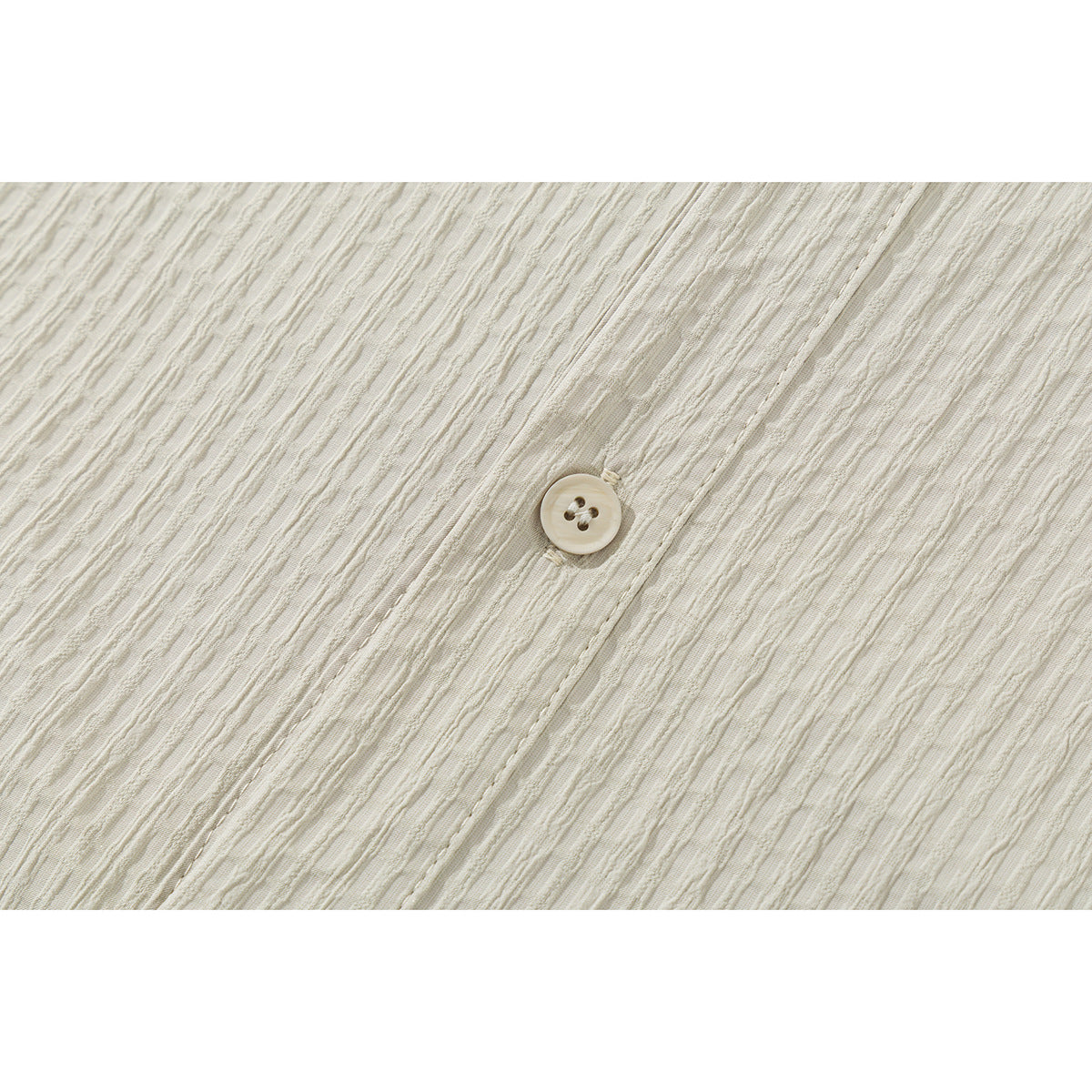 Close-up of a cream shirt button and textured fabric.