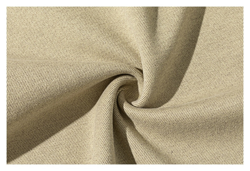 Close-up of light beige fabric gathered into a spiral fold, showing its textured surface.