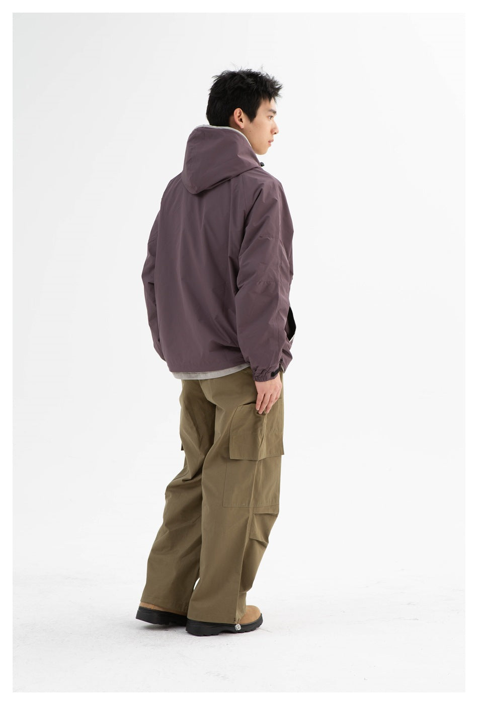 Man shown from behind in a mauve hooded jacket with olive cargo trousers.