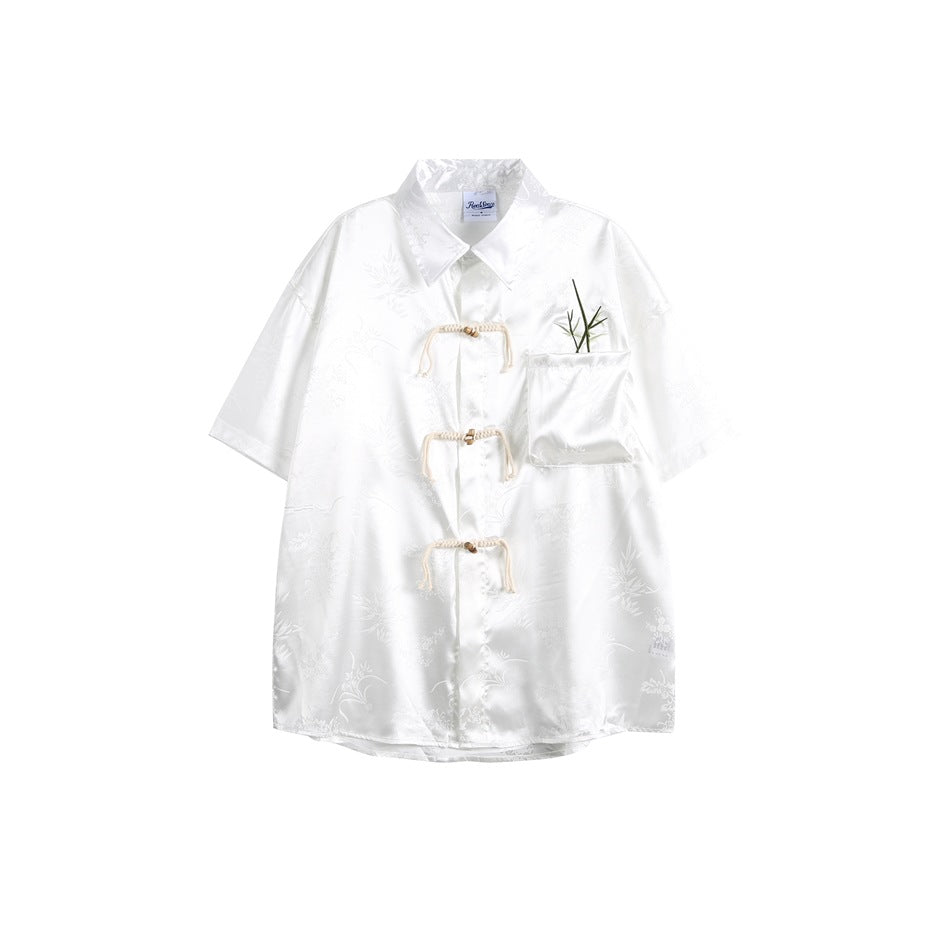 White short-sleeve satin-look jacquard shirt with three cream rope loop closures and a bamboo-embroidered chest pocket