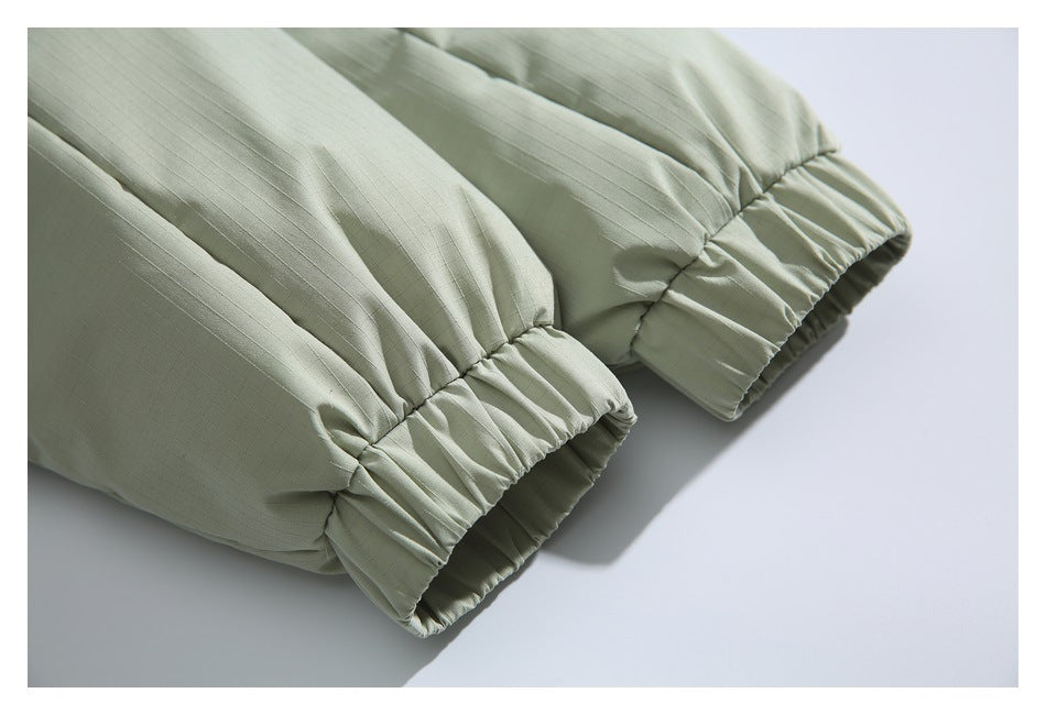 Close-up of the pale sage jacket's gathered elastic cuffs and sleeve stitching.