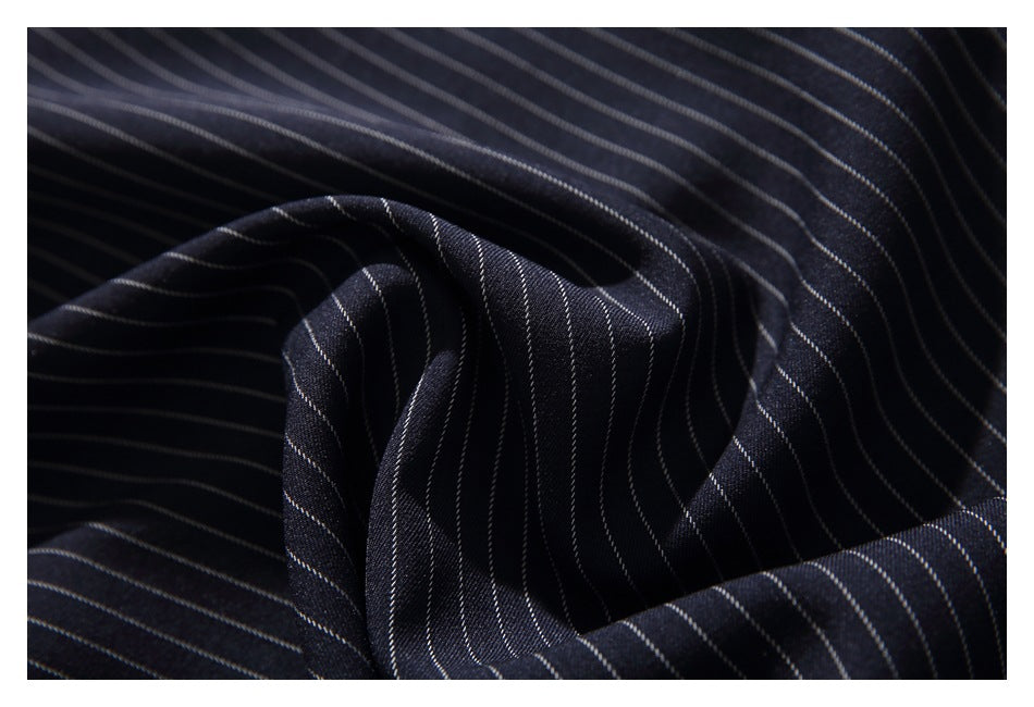 Close-up of dark navy fabric with fine white pinstripes draped in soft folds.