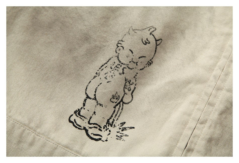 Close-up of a beige jacket showing a small black cartoon animal graphic.