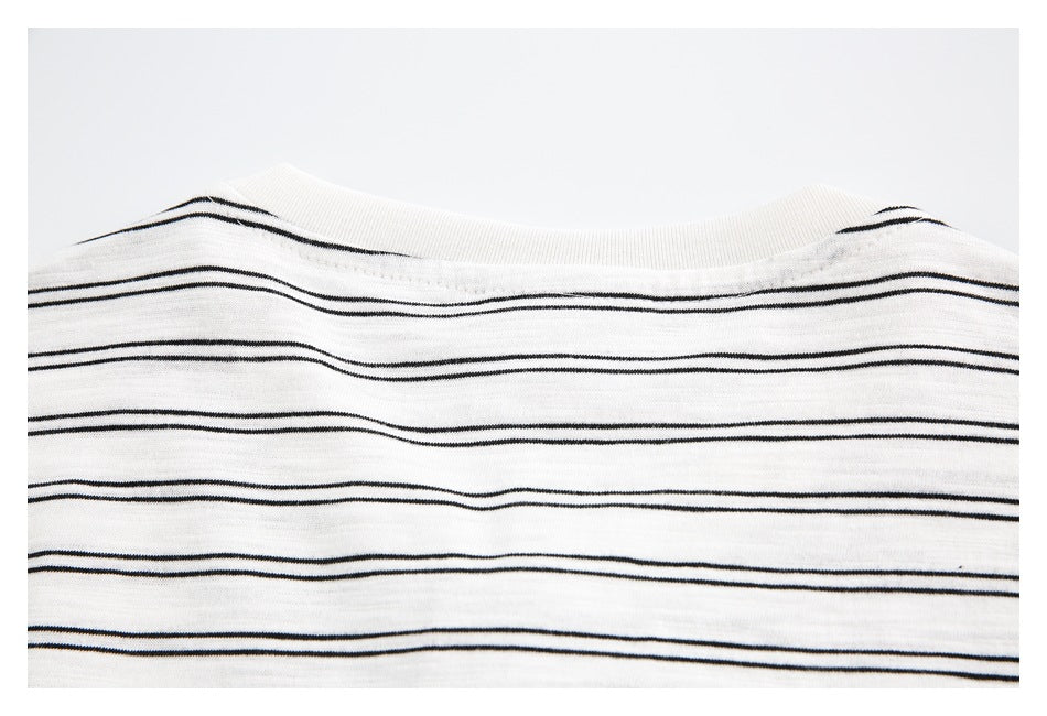 Close-up of a white knit garment with thin black horizontal stripes and a ribbed neckline.