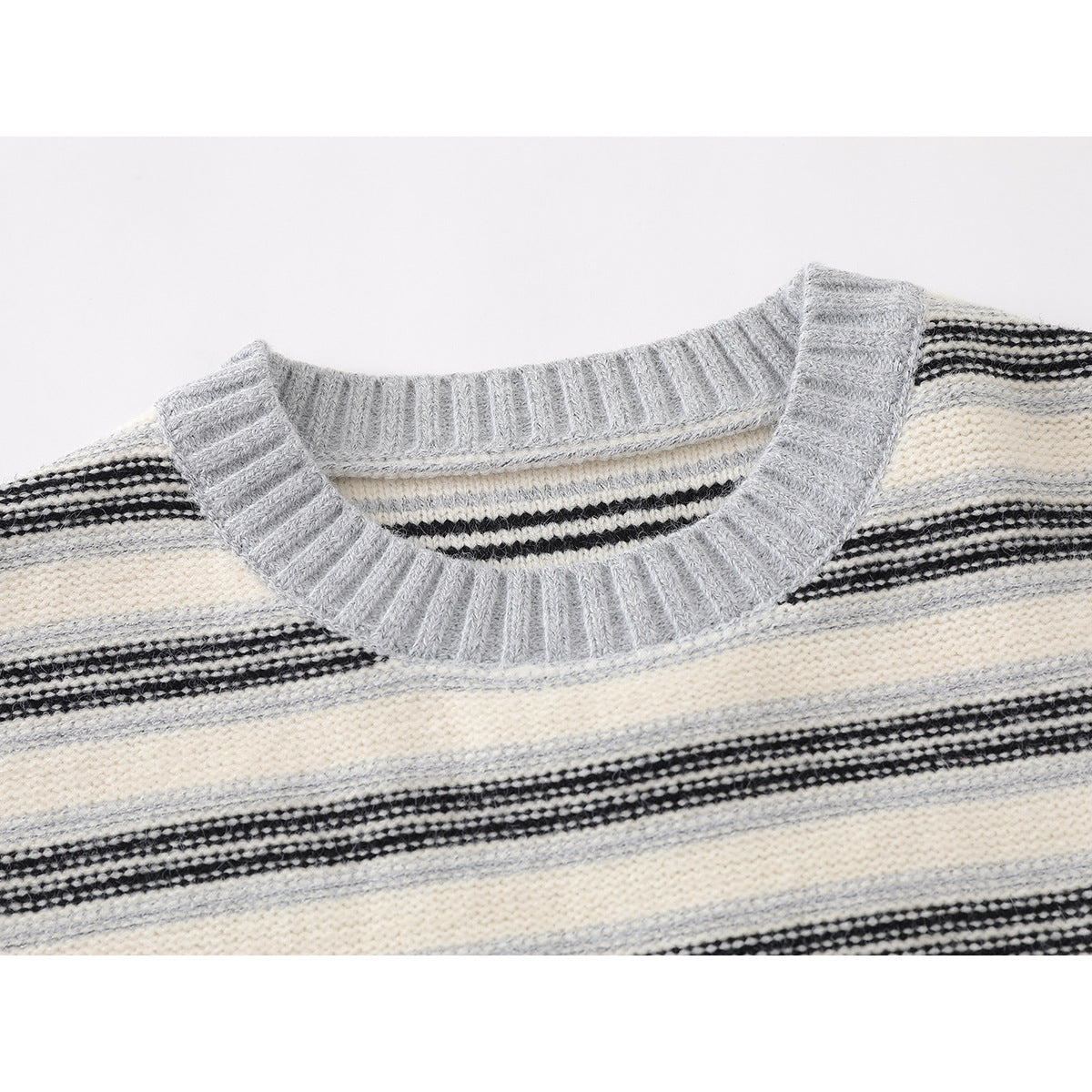 Close-up of a gray ribbed crew neck and cream, gray, and black striped knit sweater.