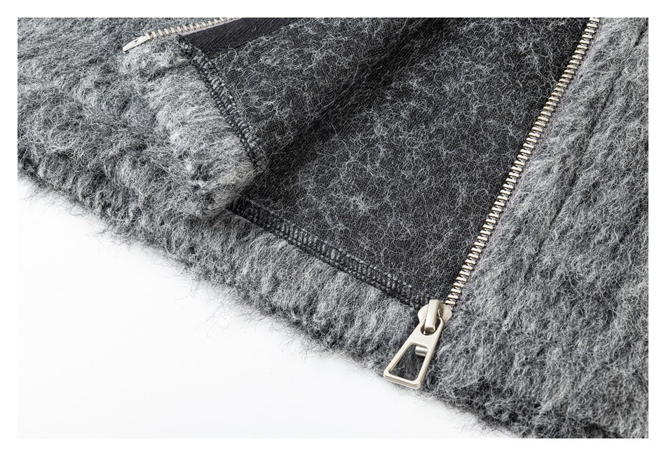 Close-up of a silver zipper and stitched seam on a charcoal-gray fuzzy garment.