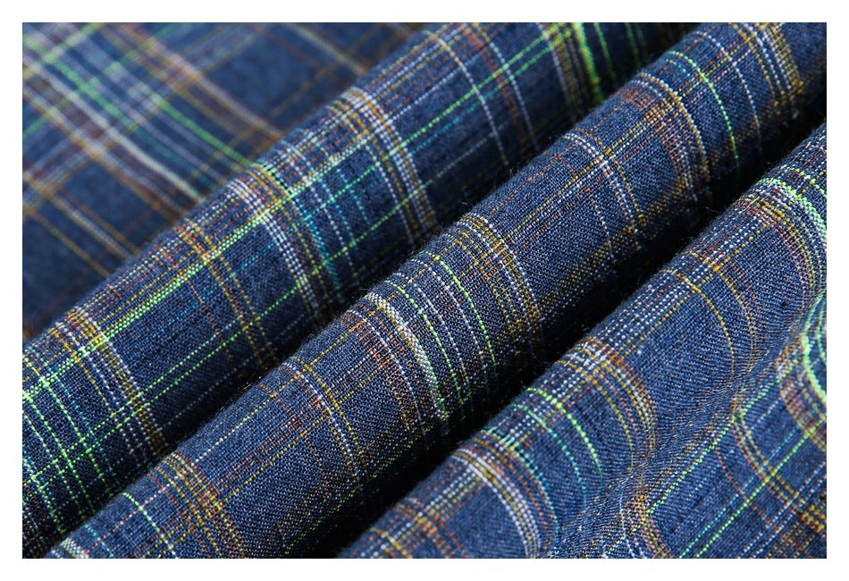 Macro view of dark blue plaid fabric folded into ridges, with fine multicolored lines.