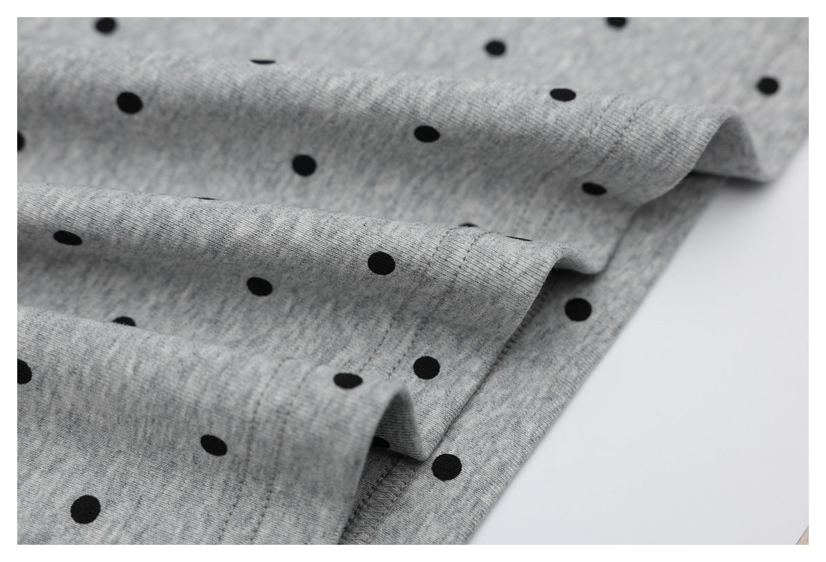Close-up of heather gray fabric with black polka dots and stitched edges.