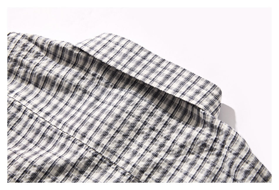 Close-up of a pointed collar on a cream and black plaid shirt.