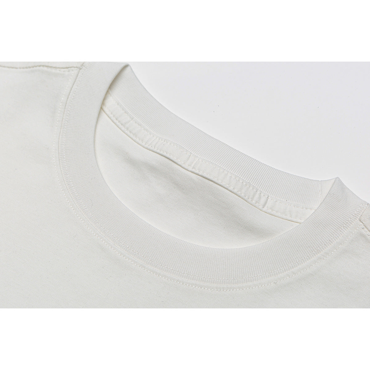 Close-up of an off-white T-shirt's ribbed crew neck and shoulder stitching.