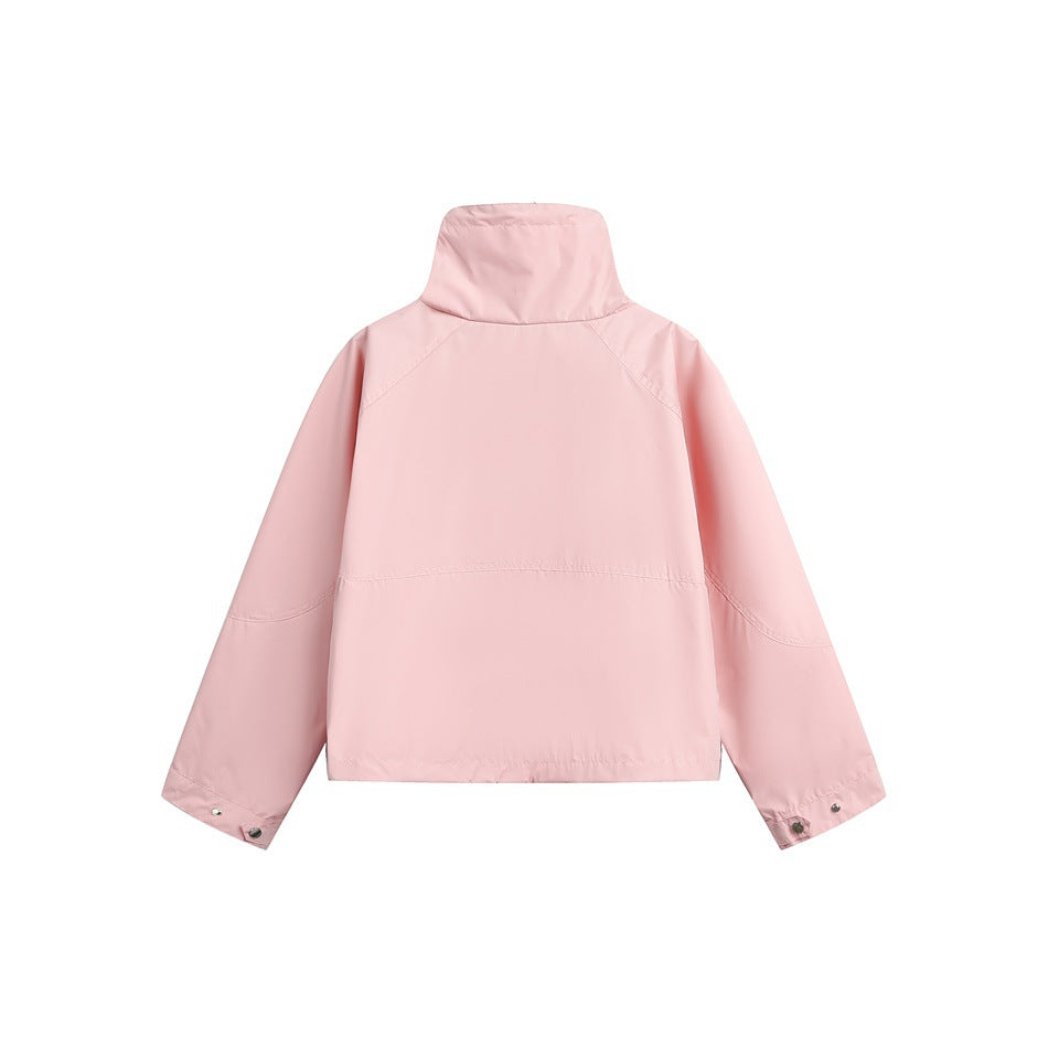 Back of a pale pink jacket with a tall collar, raglan sleeves, and snap cuffs, shown flat against white.