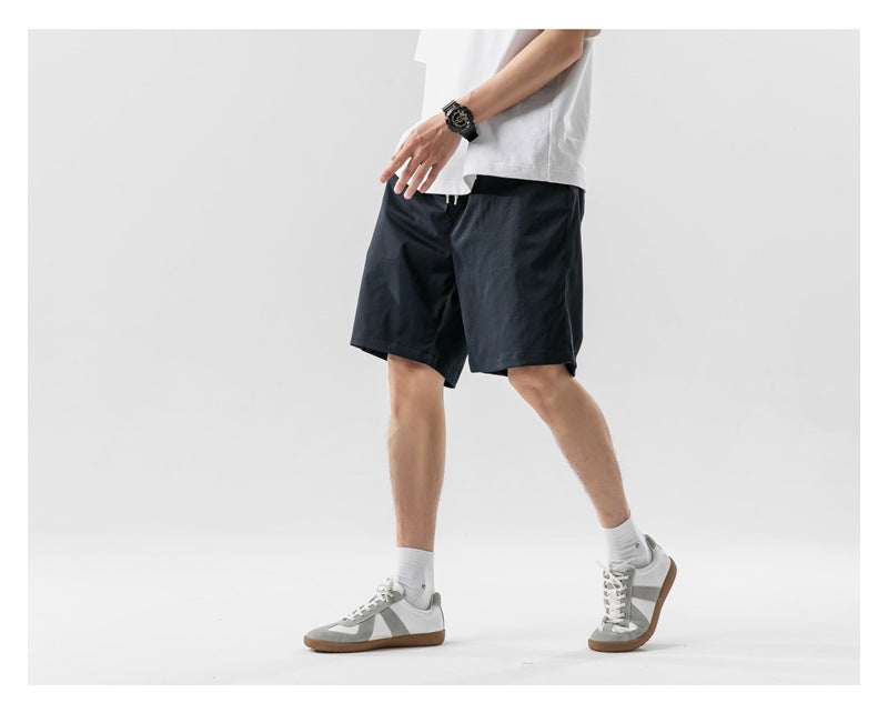 Cropped model wearing dark navy shorts, shown in a walking side-front pose.