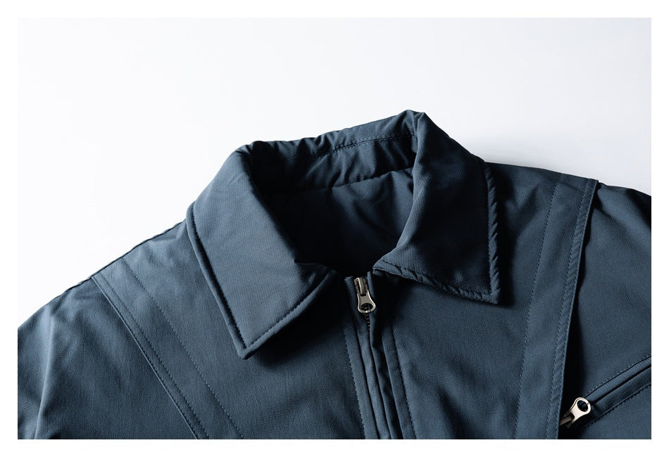 Close-up of a dark navy jacket collar, center zipper, stitched shoulder panels and a zippered chest pocket.
