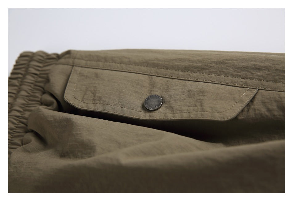 Close-up of a buttoned flap pocket on the olive-brown pants.