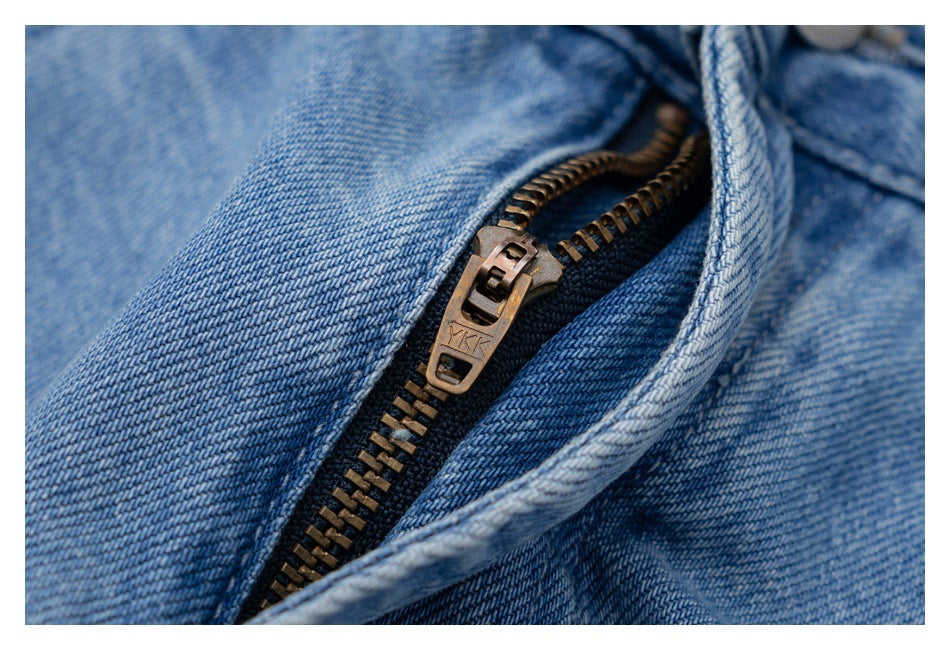 Close-up of light blue jeans with an open fly and a bronze-colored zipper.