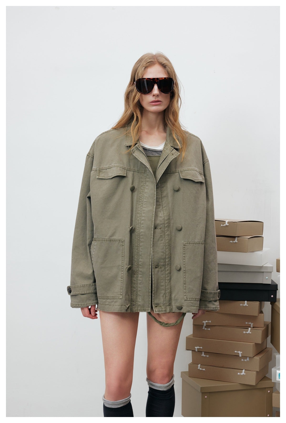 Front view of a model wearing an oversized olive utility jacket with flap chest pockets, patch pockets and front buttons.