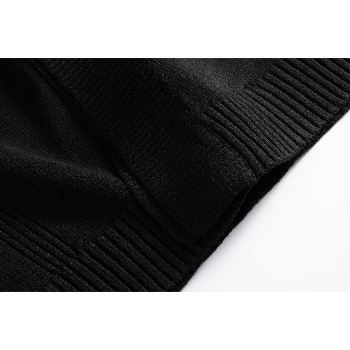 Close-up of the black cardigan’s ribbed hem and overlapping knit front edge.