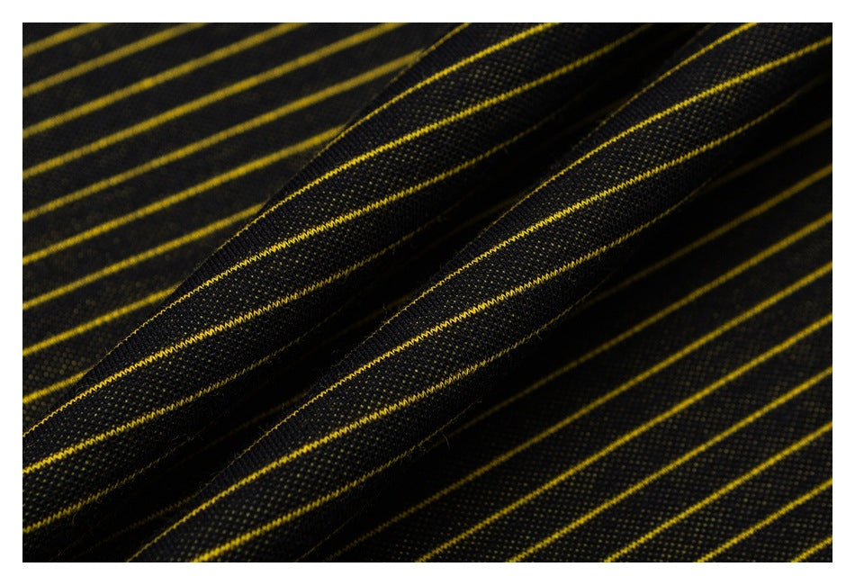 Macro view of black fabric with narrow yellow stripes, gathered into folds to show its surface texture.