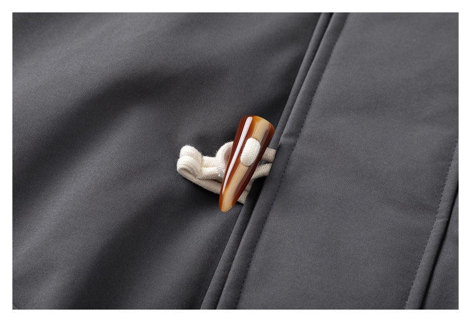 Close-up of a brown toggle and cream loop fastening on a dark gray jacket.