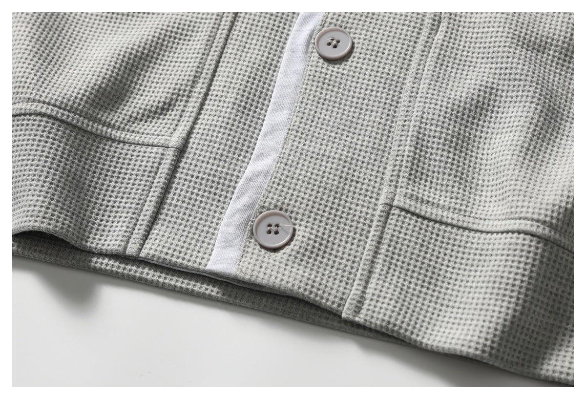 Close-up of the top's textured front, pale placket, buttons, and lower patch pockets.