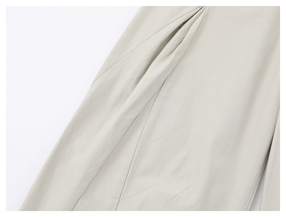 Close-up of a curved seam and pleated detail on the light ivory trouser leg.