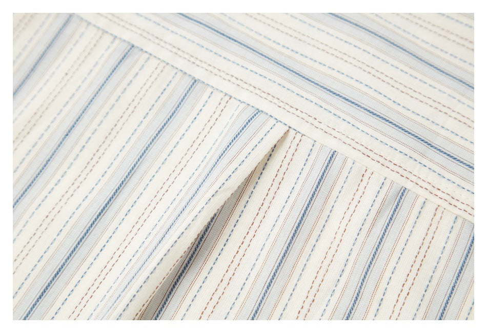 Close-up of a seam joining striped cream fabric panels, with blue and brown lines.