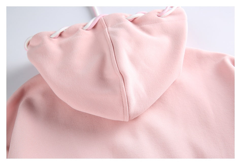Close-up of a pale pink hoodie showing its hood and matching drawstrings.