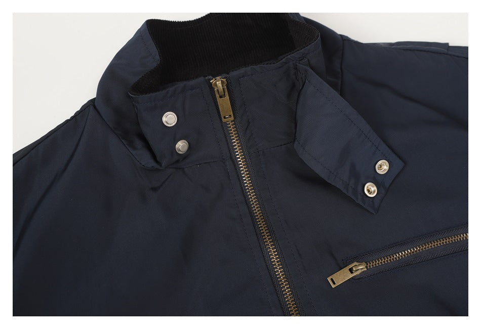Close-up of the navy jacket's open snap-tab collar, brass-tone front zipper, and chest zip pocket.