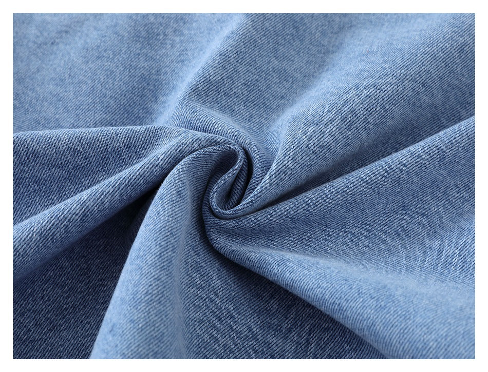Close-up of blue denim fabric twisted into soft folds, showing its diagonal weave.