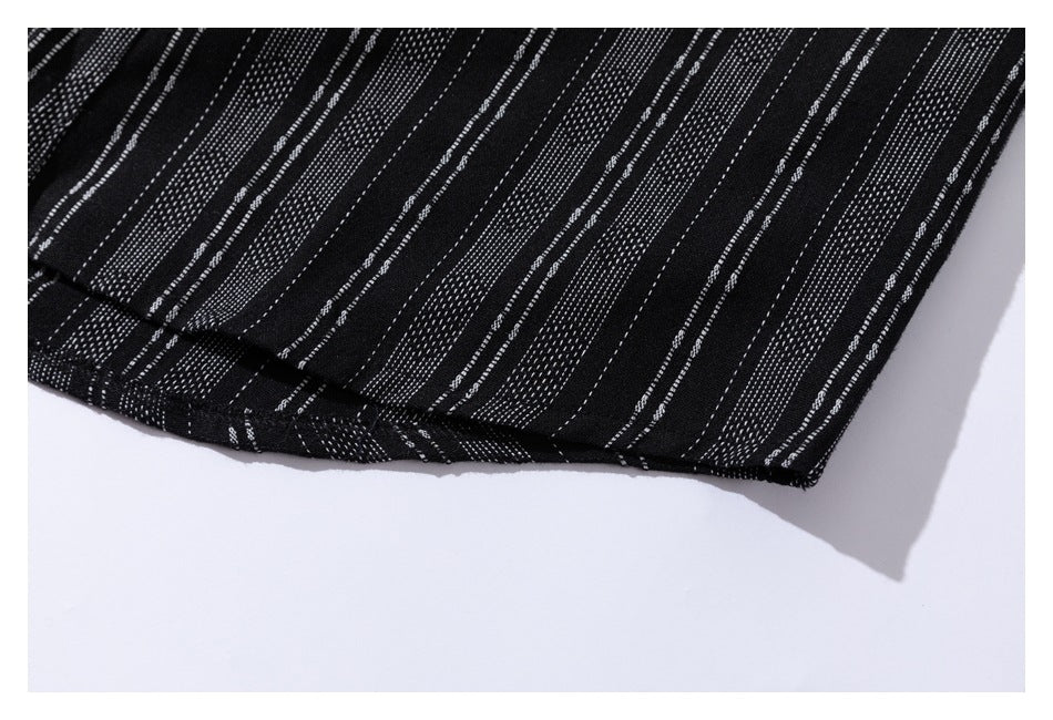 Close-up of the curved hem of black fabric patterned with irregular white dashed stripes.