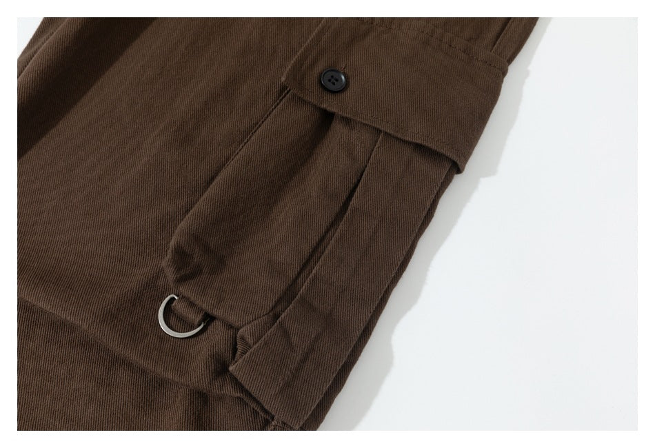 Close-up of a brown cargo pocket flap with a black button and metal D-ring.