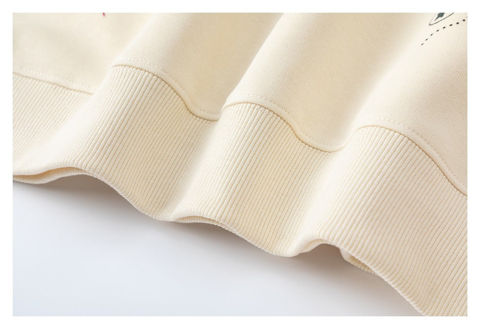 Close-up of the cream sweatshirt’s ribbed hem and stitching.