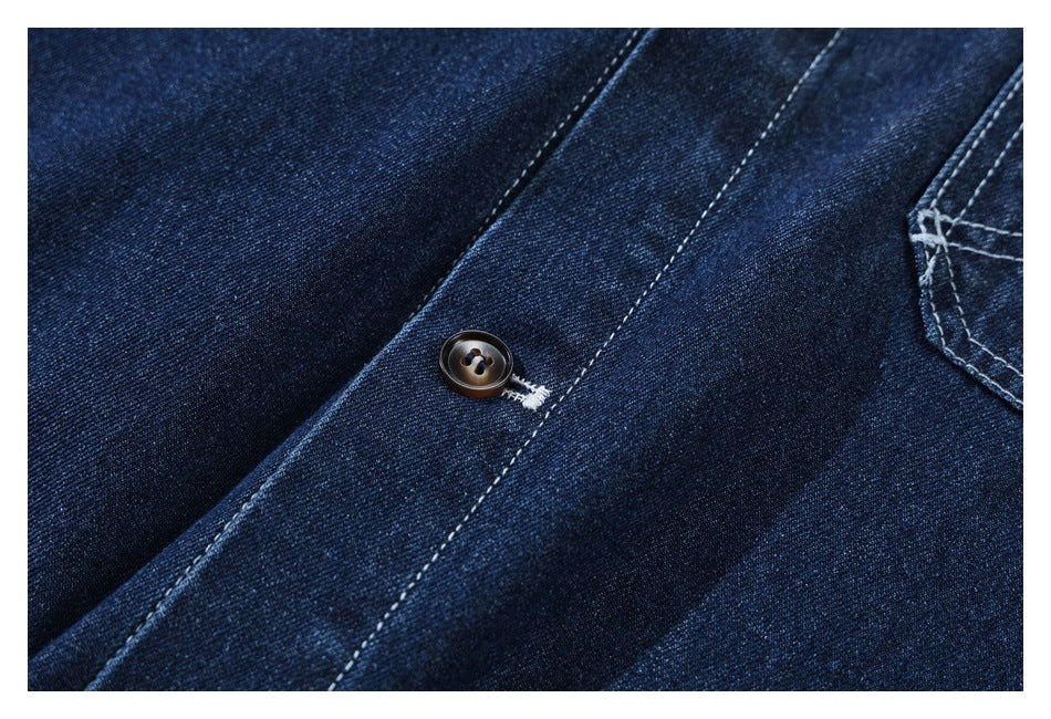 Close-up of a dark button and contrast stitching on the front placket of a dark indigo denim shirt.
