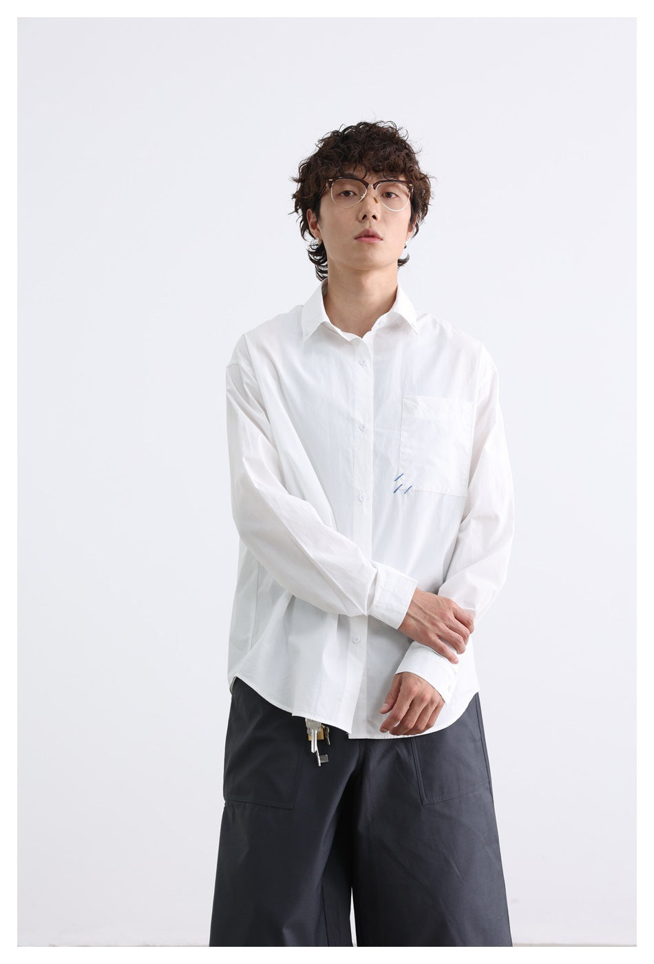 Front view of a model wearing a white button-down shirt with a chest pocket and charcoal shorts.
