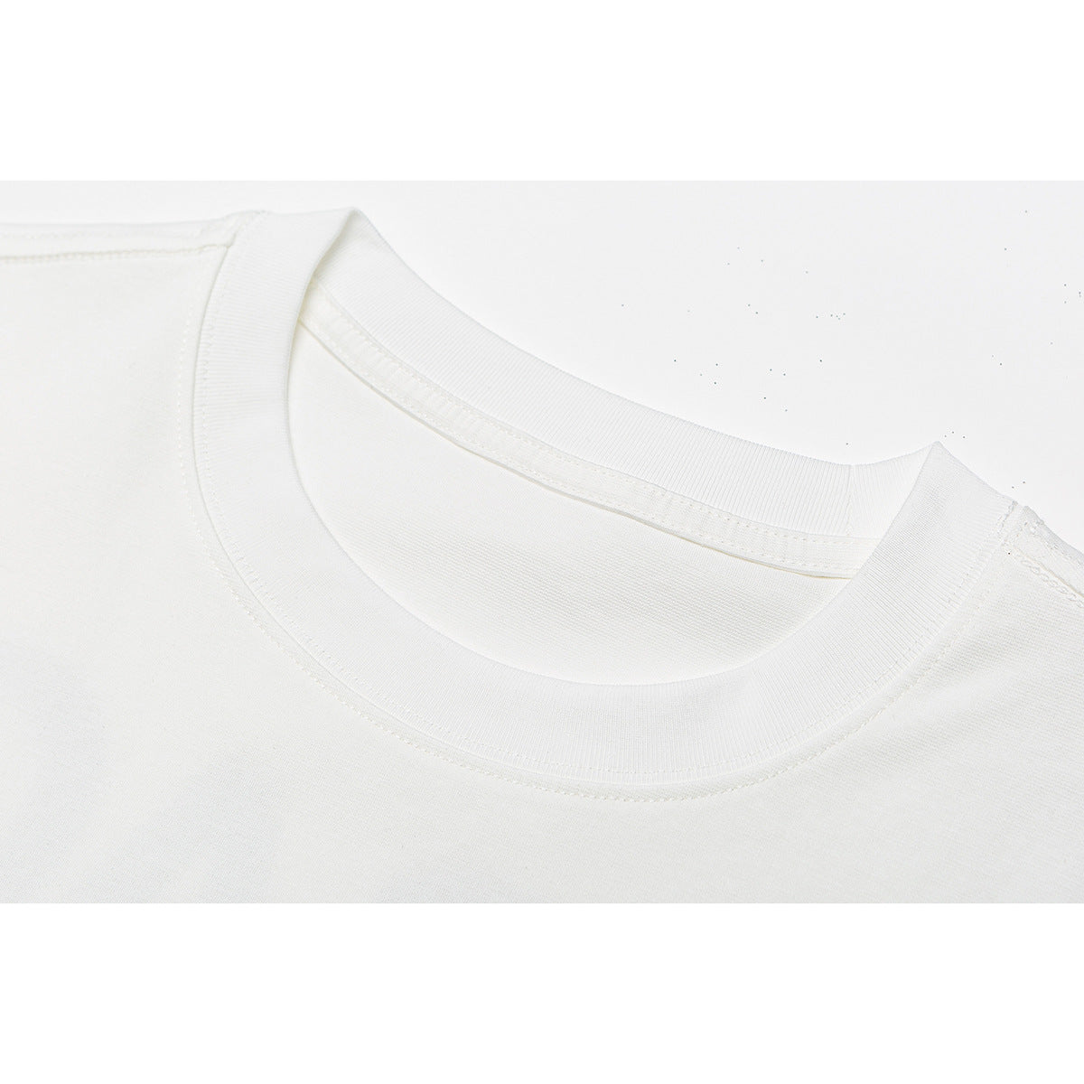 Close-up of a white T-shirt's ribbed crew neckline and shoulder stitching.