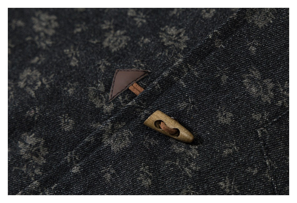 Close-up of dark floral-patterned fabric with a wooden toggle button and triangular accent.
