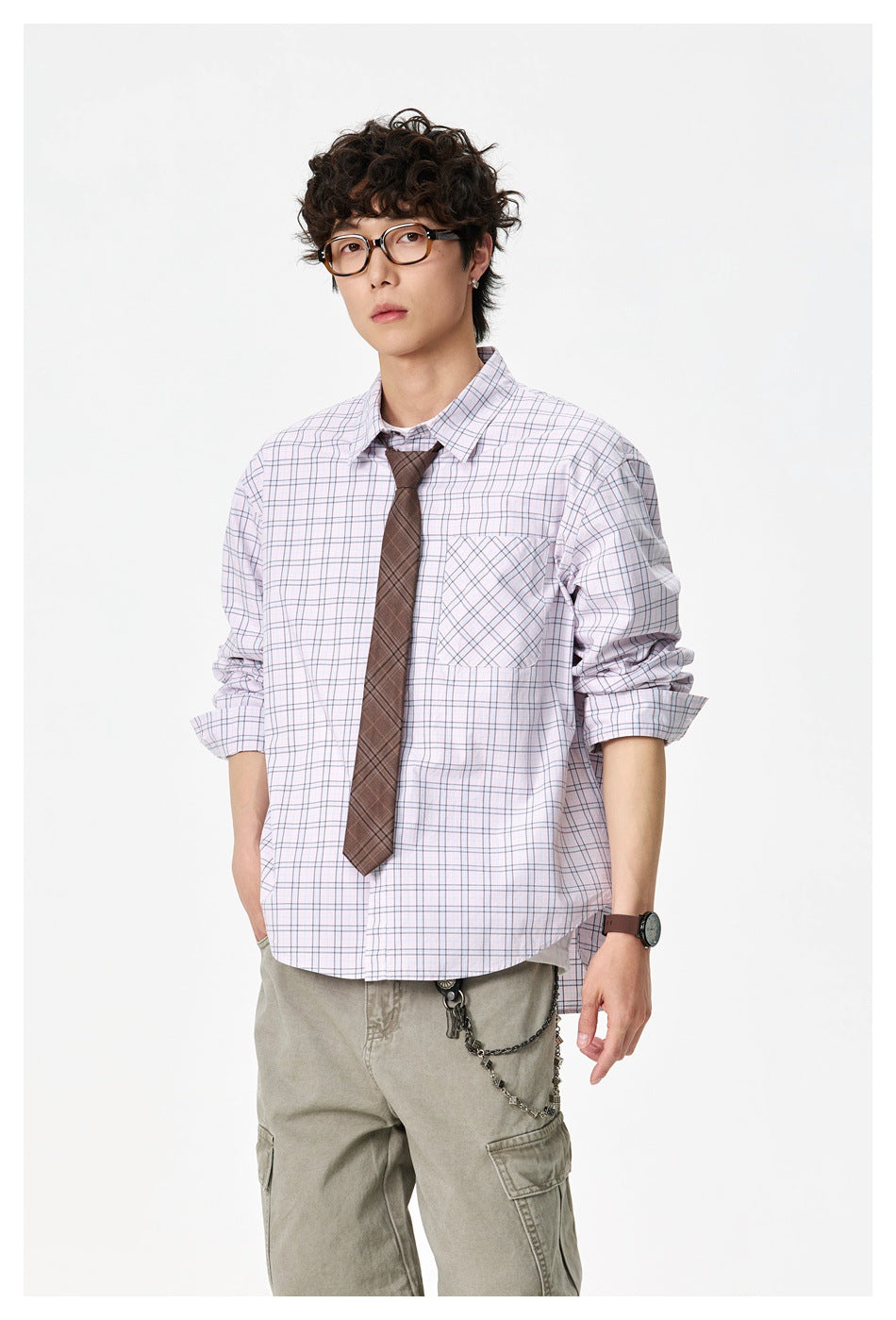 Model wearing a pale lavender plaid button-down shirt with a diagonal-plaid chest pocket and brown tie, shown with cargo