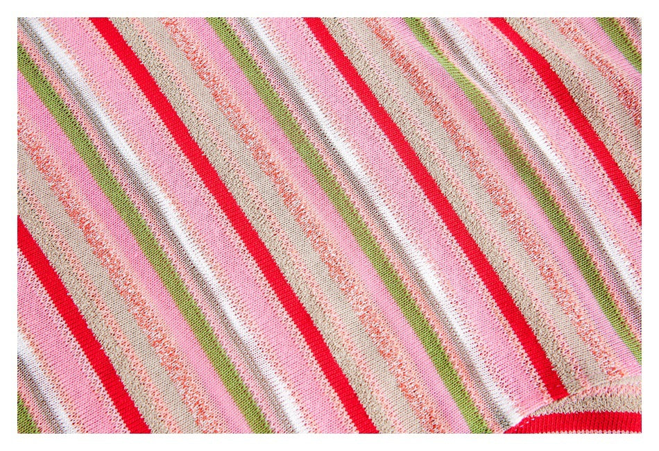 Close-up of knitted fabric with diagonal stripes in pink, red, green, white, and beige.