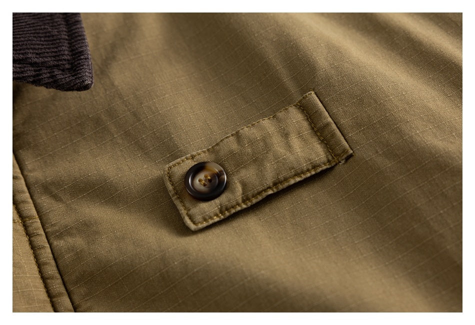 Close-up of a brown button and stitched tab on an olive-brown jacket.