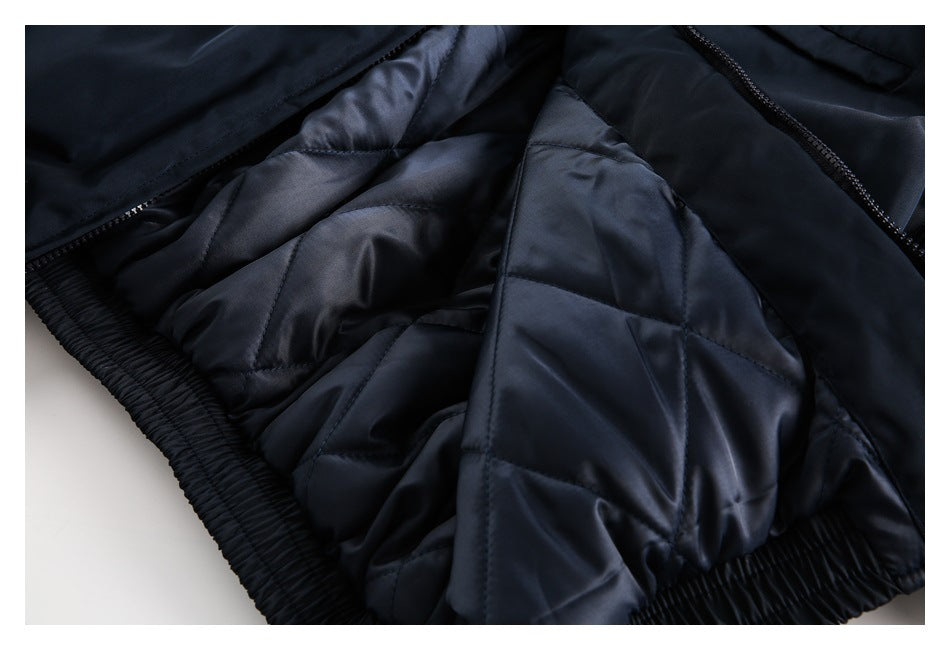 Close-up of the opened dark navy garment, showing quilted lining, zipper and elastic hem.