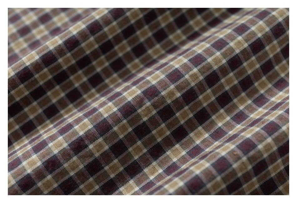 Macro view of brown, burgundy, and tan plaid fabric arranged in soft folds.