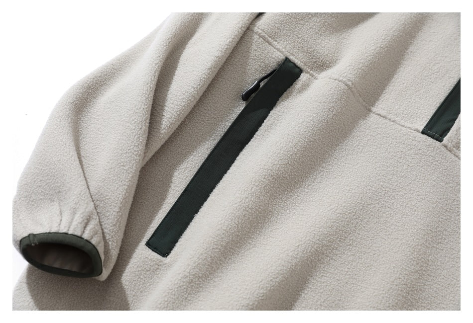 Close-up of the cream sherpa jacket’s dark green-trimmed chest pocket and cuff.