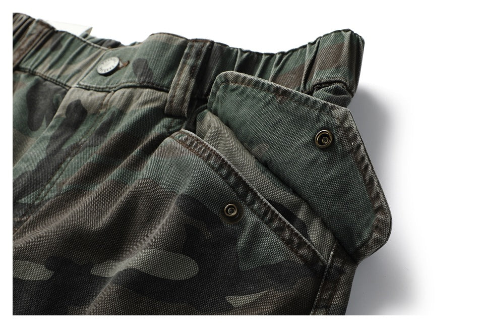 Close-up of the camouflage trousers’ gathered waistband, button, and open fly fastening.
