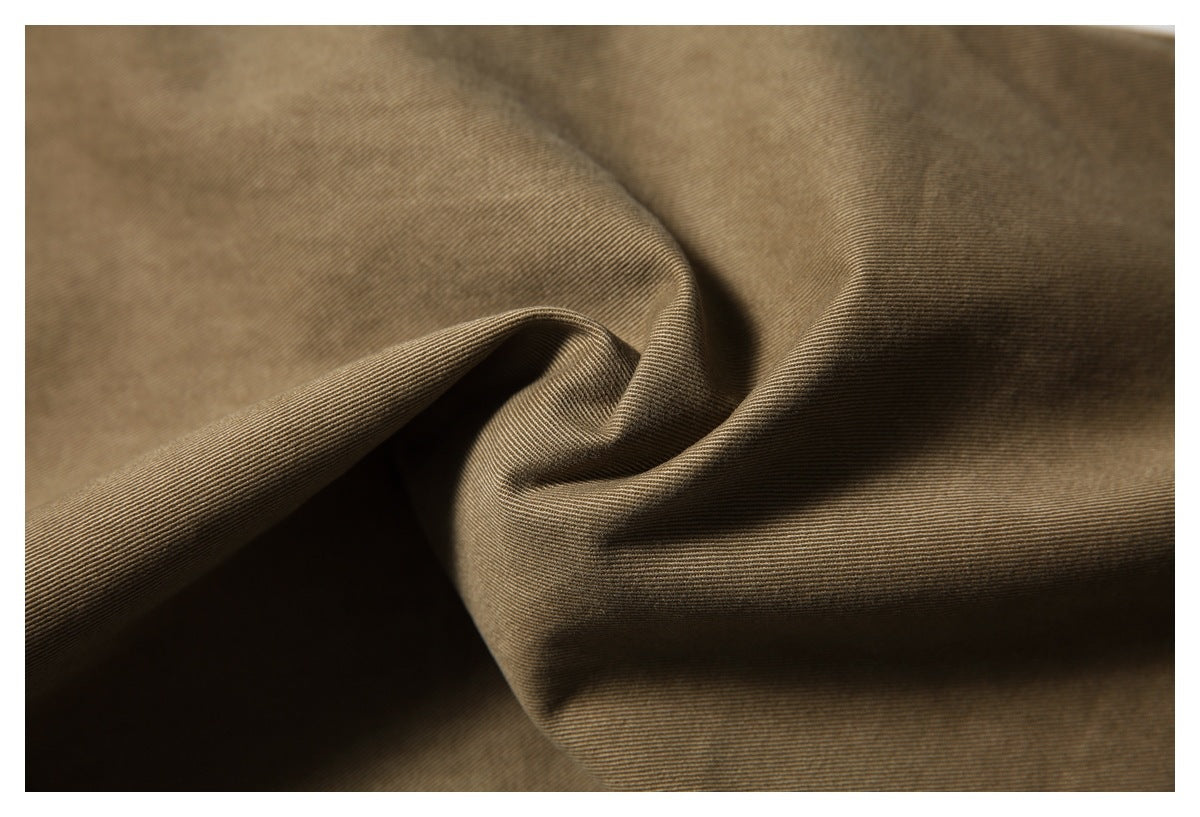 Close-up of brown fabric draped into folds, showing its fine diagonal weave.